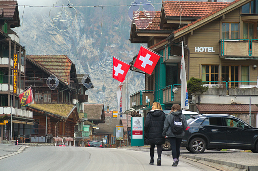 Lauterbrunnen, Switzerland - December 1, 2022: Two women walking on a street in the village of Lauterbrunnen on a cold December day