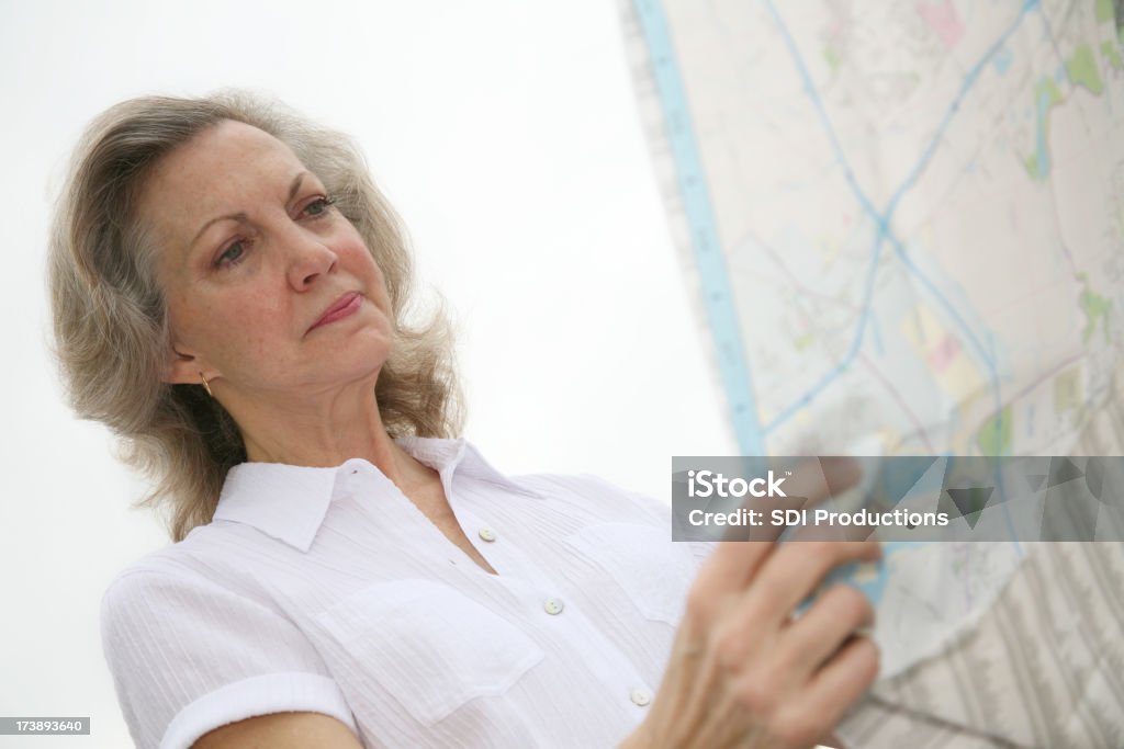 Isolato anziani donna guardando una mappa - Foto stock royalty-free di Adulto