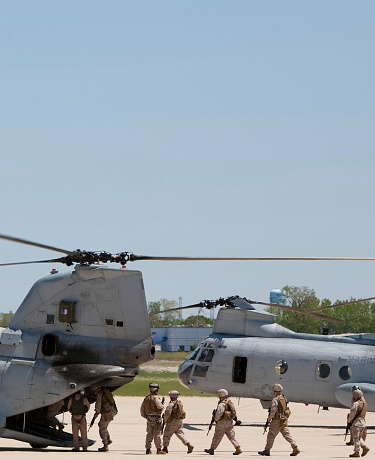 a squad of US marines load up into the back of a chinook type helicopter.