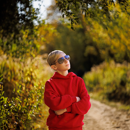 A teenager in a fall park pondered. A boy in a red suit in a park in the fall.