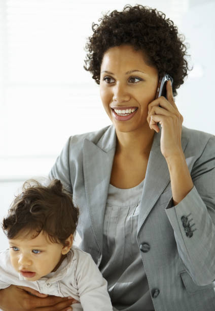 istock Businesswoman holding her daughter while using a mobile phone 173895398