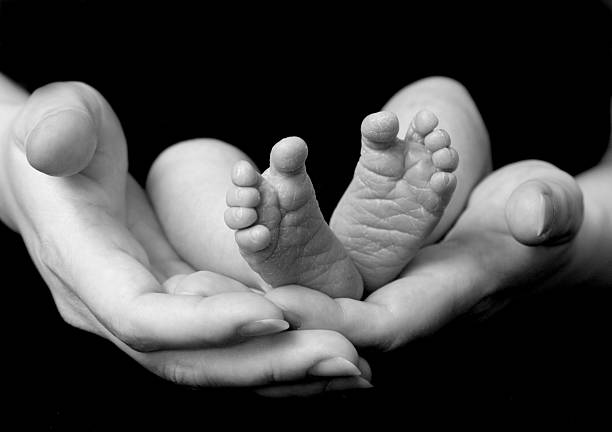 生まれたばかりの赤ちゃんの足を母の手 - human foot baby black and white newborn ストックフォトと画像