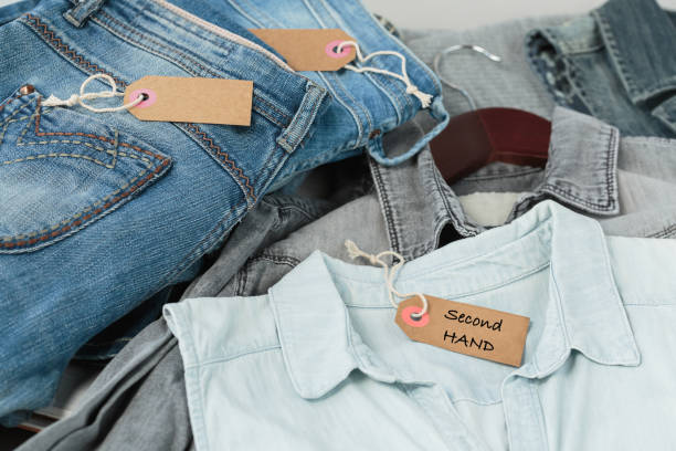 istock Stack of blue jeans, shirts and tag with inscription second hand 1738959300