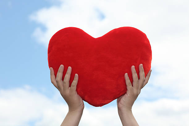 istock Heart in hands against sky 173896117