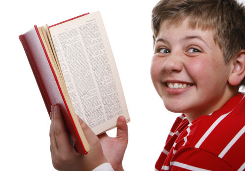 A ten year old child reading an encyclopedia. Isolated on a white background.