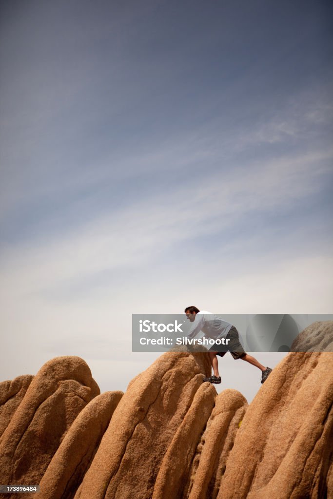 Uomo cercando di ottenere su boulders nel deserto - Foto stock royalty-free di Affari