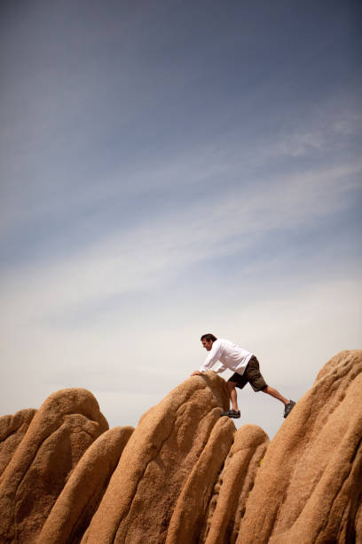 istock Man struggling to get over boulders in desert 173896484