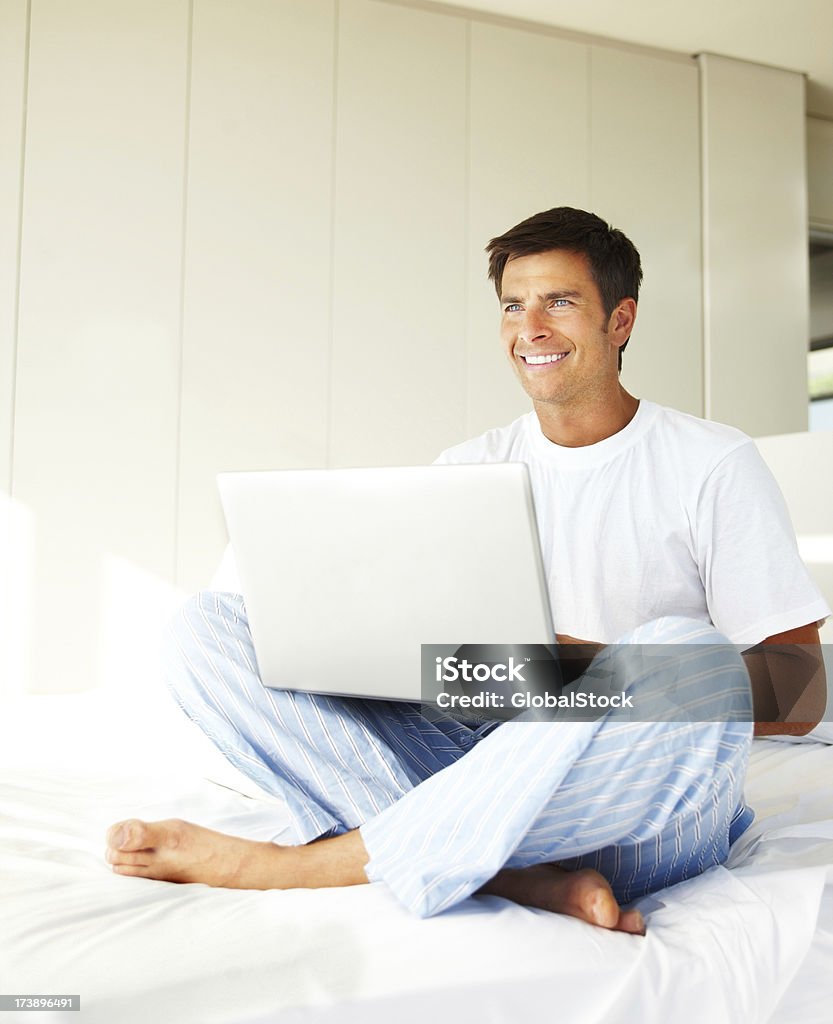 Young man using a laptop and smiling Young man using a laptop and smiling at home 20-24 Years Stock Photo