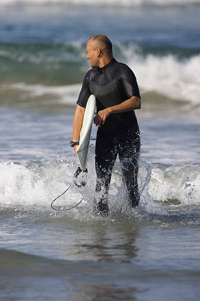 Surfer leaving the water in Huntington Beach stock photo