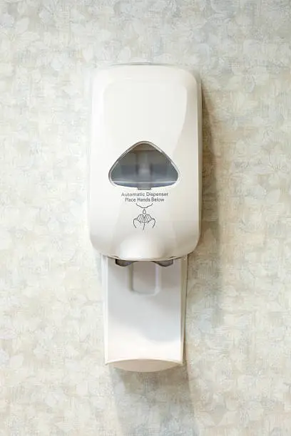 A liquid hand sanitizer soap dispenser on a wall.