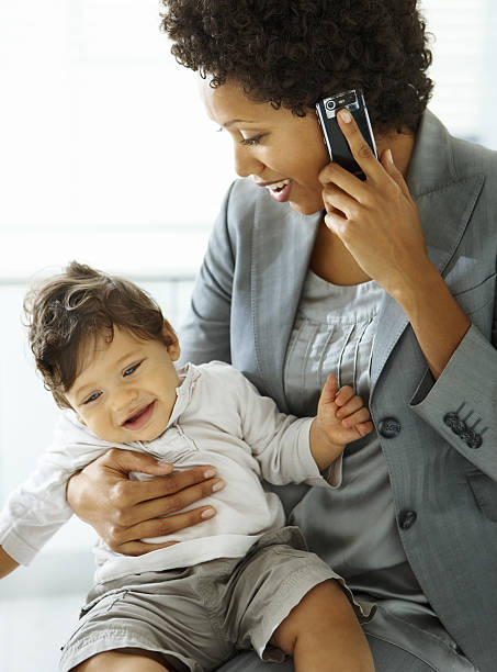 istock Businesswoman holding her daughter while using a mobile phone 173896648