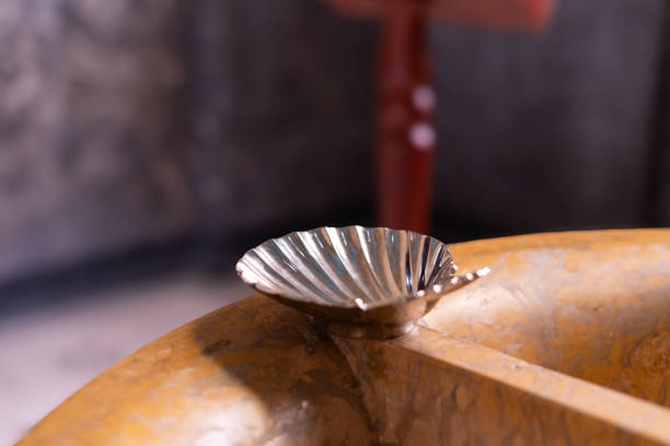 Silver baptism shell over baptismal font with blurred background before baptism