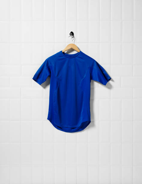 Blue Football Shirt Royal blue football shirt hanging on a white tiled wall with a wooden hanger. copy spaceClick on the link below to see more of my sport images blue soccer shirt stock pictures, royalty-free photos & images