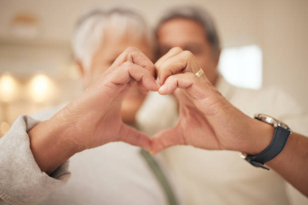 istock Heart hands, emoji and senior couple in home with commitment, support and marriage in retirement together. Love sign, happy man and old woman in apartment with icon for romantic gesture of loyalty. 1738972829