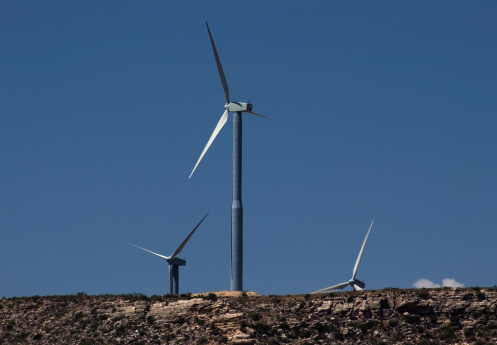 Alternative energy wind turbines on Southwest Mesa against a clear blue sky.