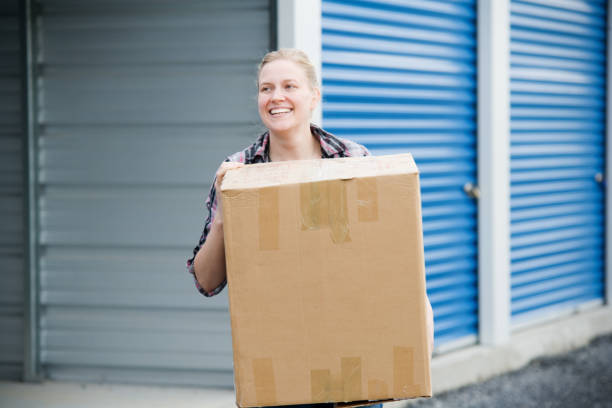 Woman With Box Outside Self Storage Unit stock photo