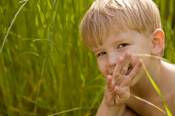 boy holds up four fingers in grass stock photo