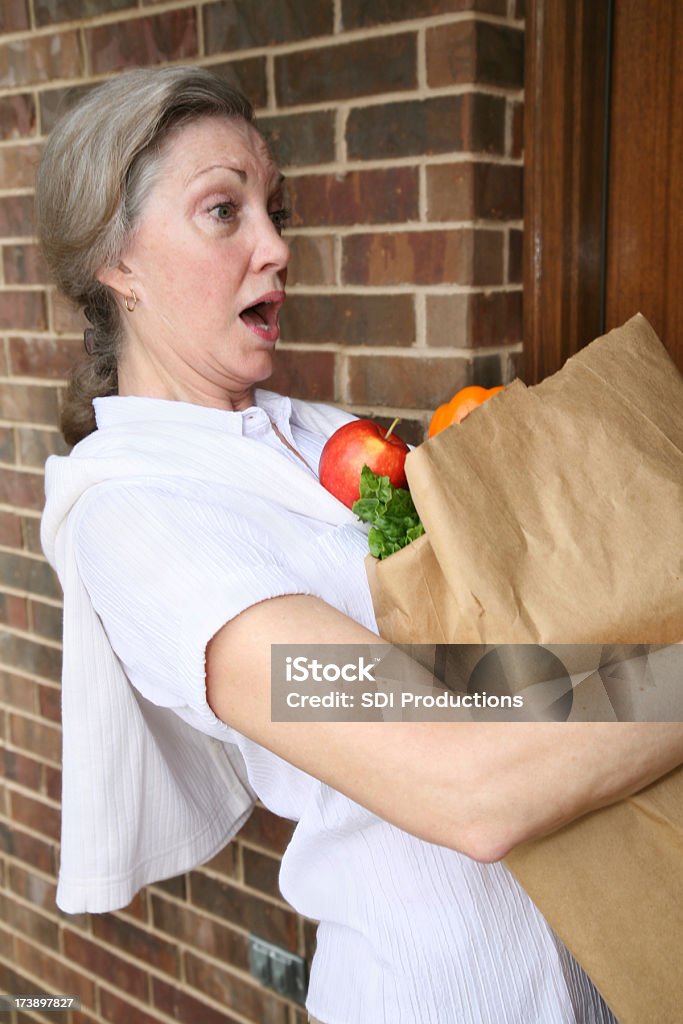 Mujer sorprendida Derramando su bolsa de compra de comestibles - Foto de stock de Mujeres maduras libre de derechos