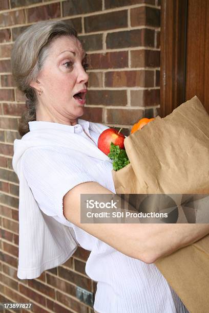 Mujer Sorprendida Derramando Su Bolsa De Compra De Comestibles Foto de stock y más banco de imágenes de Mujeres maduras