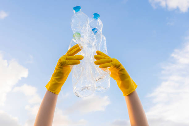 istock A young volunteer's hand lifts trashed plastic bottles into the sky. On World Environment Day 1738979017