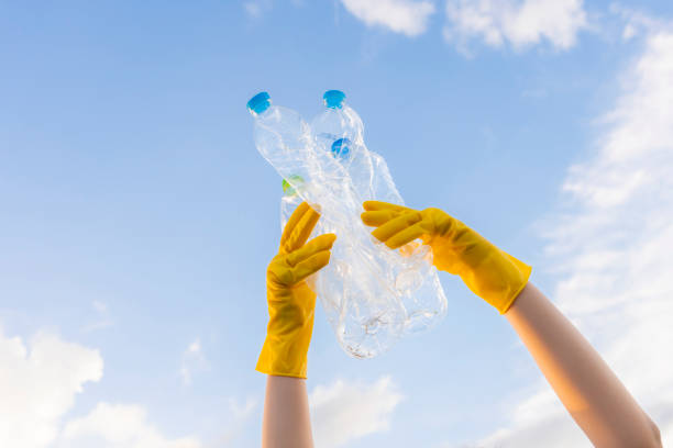 istock A young volunteer's hand lifts trashed plastic bottles into the sky. On World Environment Day 1738979018
