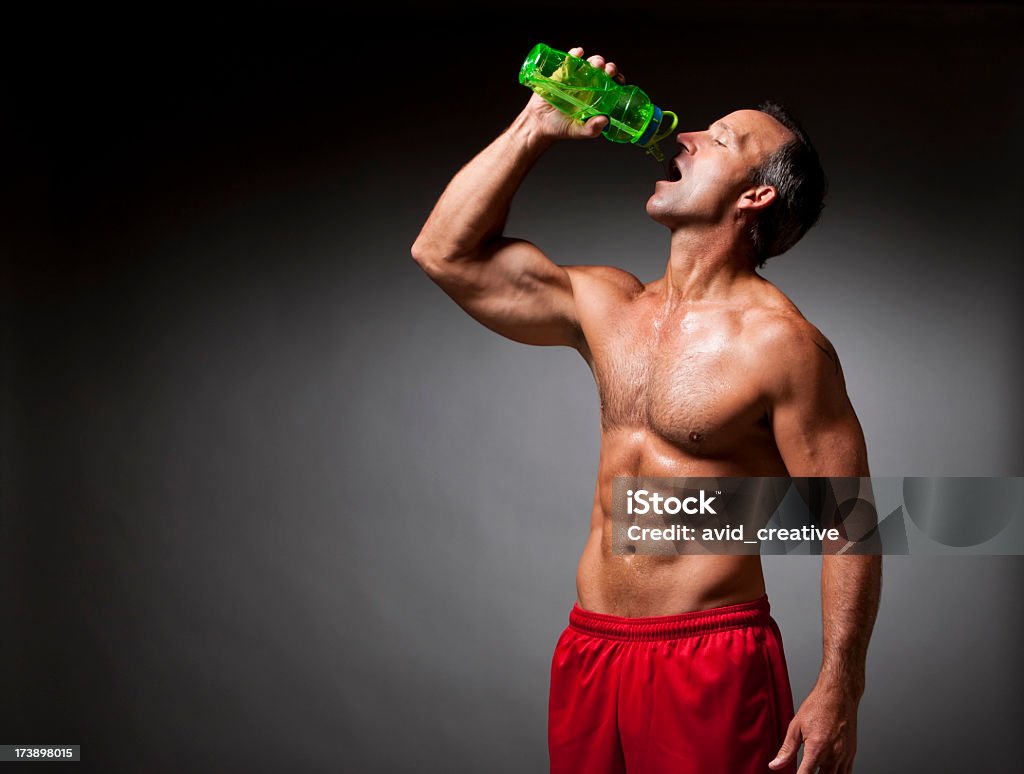Fitness: Athlete Drinking Water a very fit, shirtless 40-45 year old caucasian male drinking from a water bottle after a workout. Muscular Build Stock Photo