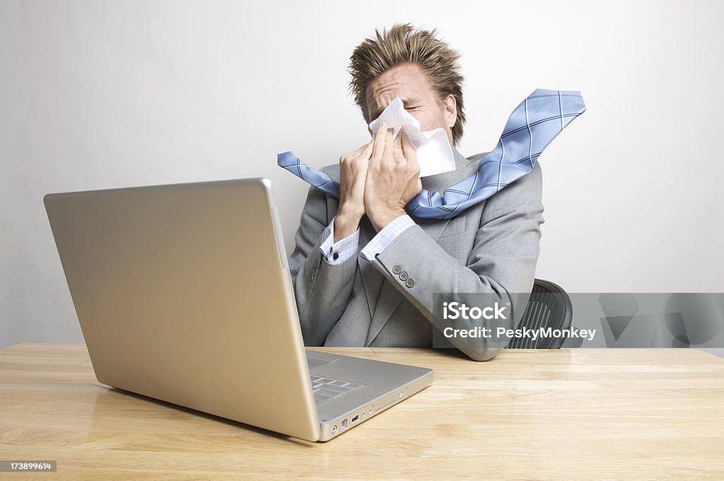 Sick Businessman su nariz soplado sentado en el escritorio de oficina - Foto de stock de Oficina libre de derechos