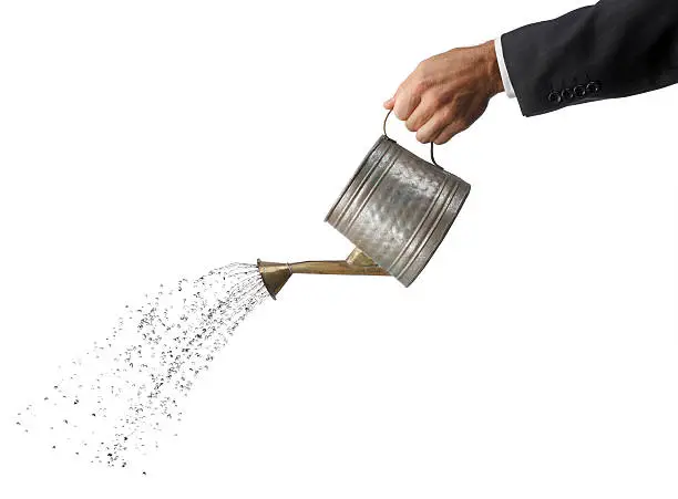A businessman pouring water out of a watering can.