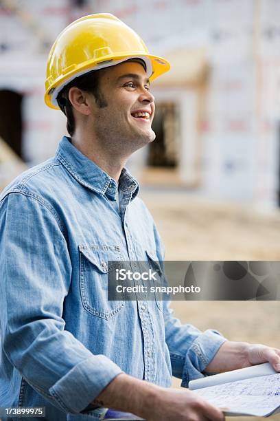 Homem A Segurar Projectos De Construção Usando Capacete De Proteção - Fotografias de stock e mais imagens de Adulto