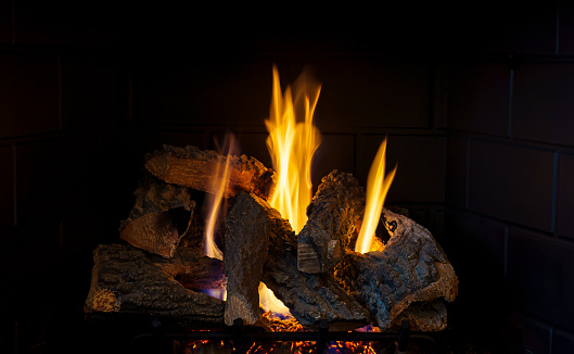 Fireplace Replacement Background Image - Flames glowing while burning logs in natural gas home fireplace.