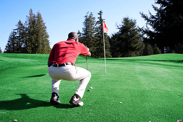 adulto afro americano uomo erba di campo da golf verde con bandiera - golf putting determination focus foto e immagini stock