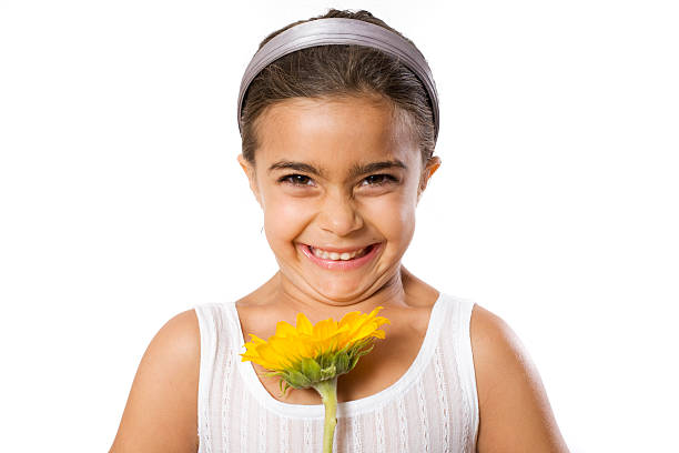 Little girl giggling while holding a flower stock photo