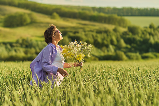 Elderly woman in stylish clothing relaxing in a lush meadow, embodying the fulfilling experiences offered in senior communities.