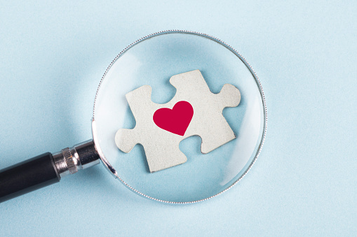 Heart Shape on puzzle piece with magnifying glass