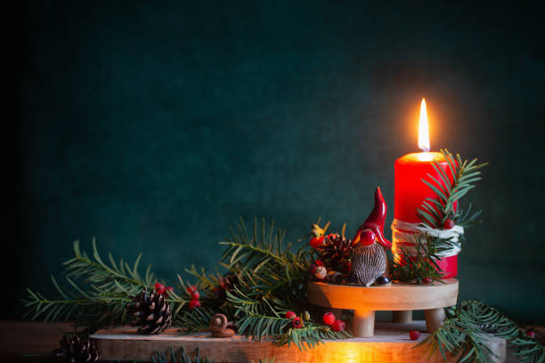 istock red burning candle with ceramic gnome in red hat with christmas branches on dark green background 1739020062