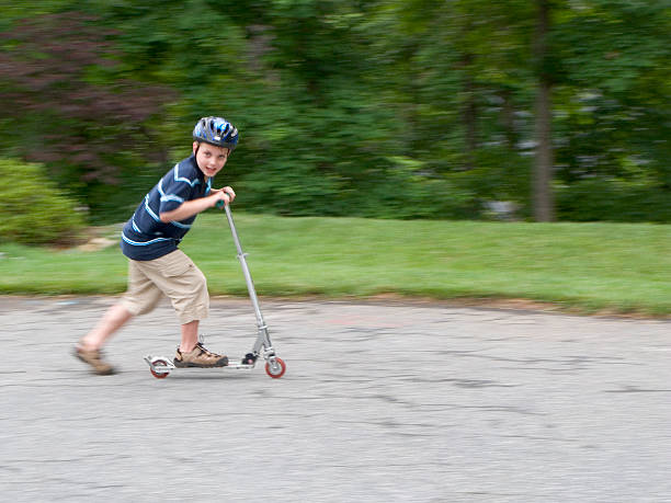 istock Boy Riding Fast On Scooter With Helmet Looking At Camera 173902085