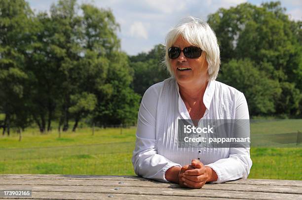 Freundliche Senior Woman In White Sitting Im Picknicktisch Im Freien Stockfoto und mehr Bilder von 60-64 Jahre