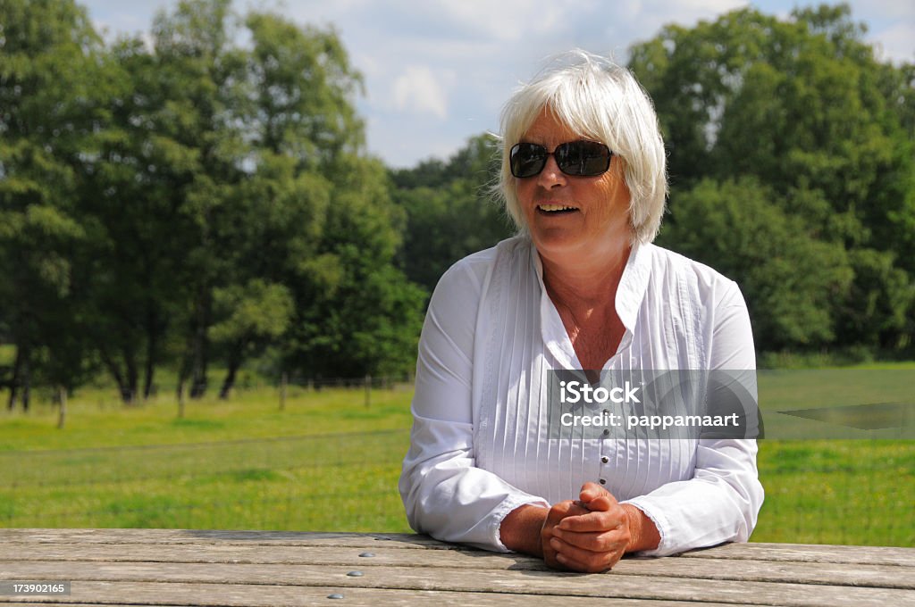 Para mulher sênior em branco sentado ao ar livre na mesa de piquenique - Foto de stock de 60 Anos royalty-free