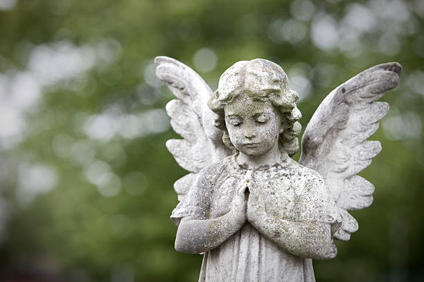Stone cherub praying Stone cherub praying in graveyard. Taken with Canon 1Ds MarkIII cemetery stock pictures, royalty-free photos & images