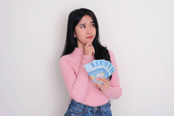 istock Young Asian women thinking something while holding money 1739025780