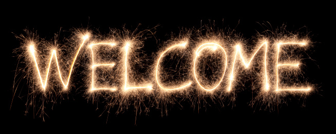 Welcome written with a sparkler on a black background.
