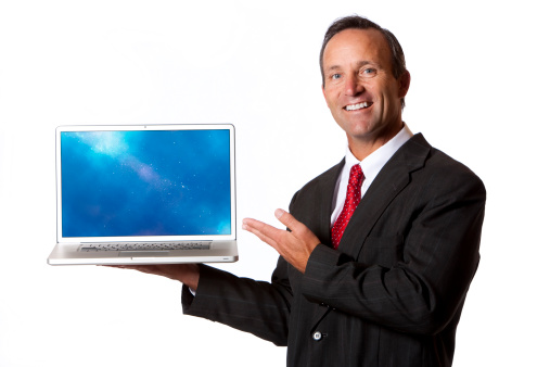 A handsome 40-45 year old caucasian businessman with a big smile presenting on a modern laptop--holding it to the side. isolated on a white background.