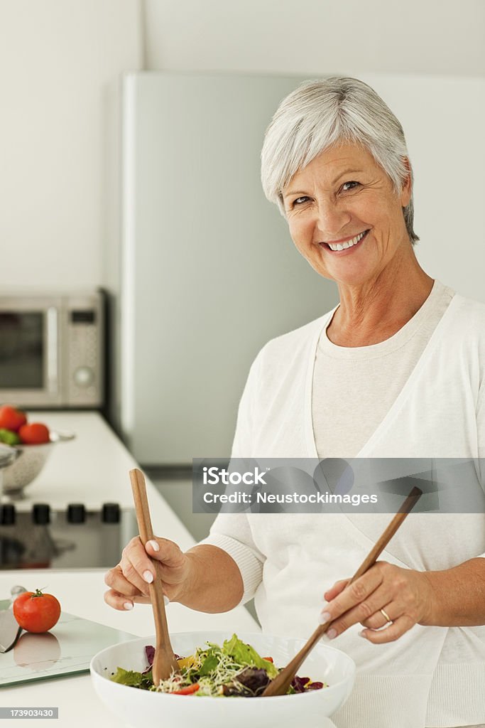 Heureuse Femme âgée mélanger légumes dans la cuisine - Photo de 60-64 ans libre de droits