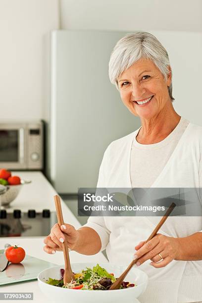 Felice Donna Senior Con Un Mix Di Verdure In Cucina - Fotografie stock e altre immagini di 60-64 anni