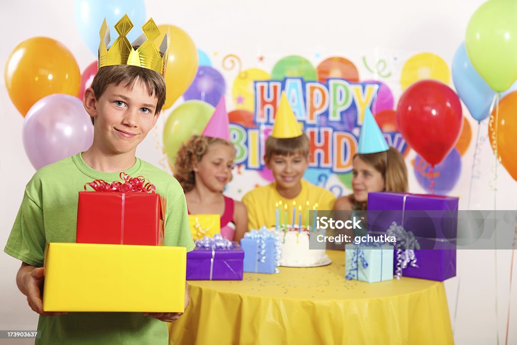 Boy's Birthday Party Children having fun at a birthday party.  Child standing in front holding birthday presents. 10-11 Years Stock Photo