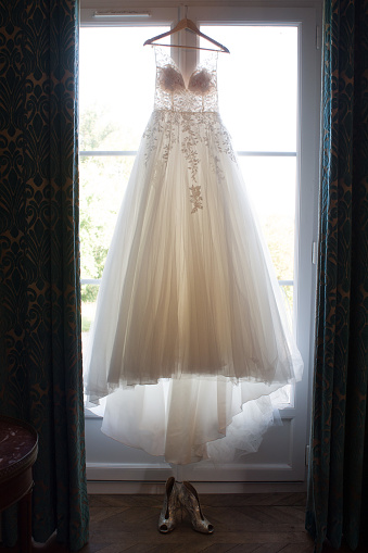 A wedding dress hanging in front of a window