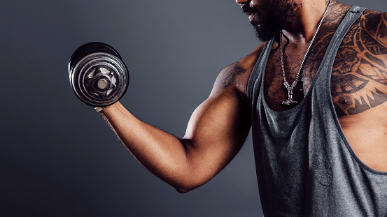 Black man's muscular arm holding a dumbbell in a biceps exercise