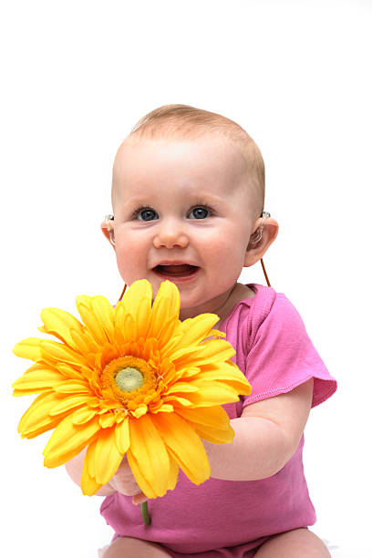 A baby girl in pink holding a flower stock photo