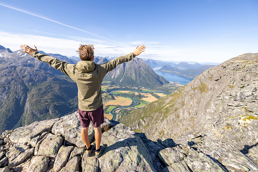 Young man hiking in a beautiful scenery in Summer enjoying nature and the outdoors.\nNorway