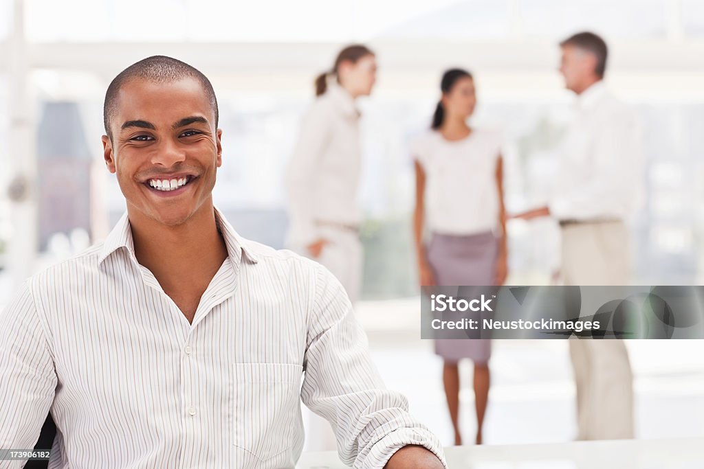 Empresário sorrindo com colegas no fundo - Foto de stock de 20-24 Anos royalty-free